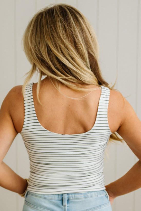 Person wearing a striped tank top with a neutral background