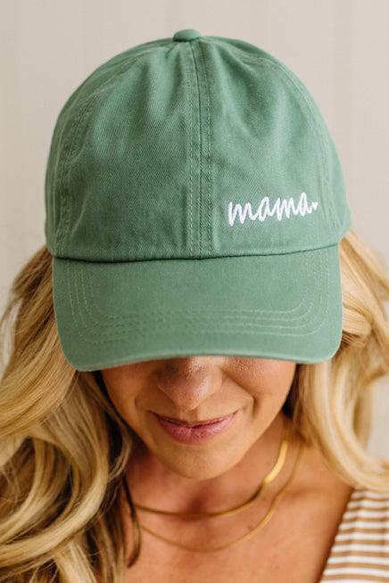 Green cap with 'mama' text worn by a person with blonde hair.