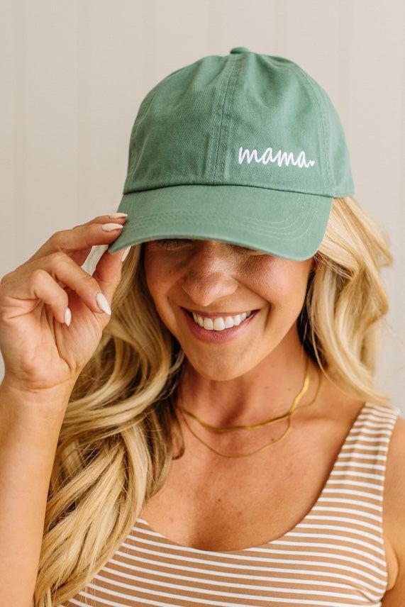 Woman wearing a green 'mama' cap with a plain background
