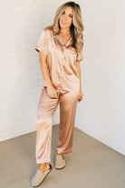 Blonde woman wearing a silk pajama set with white piping.