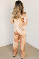 Blonde woman wearing a silk pajama set with white piping.