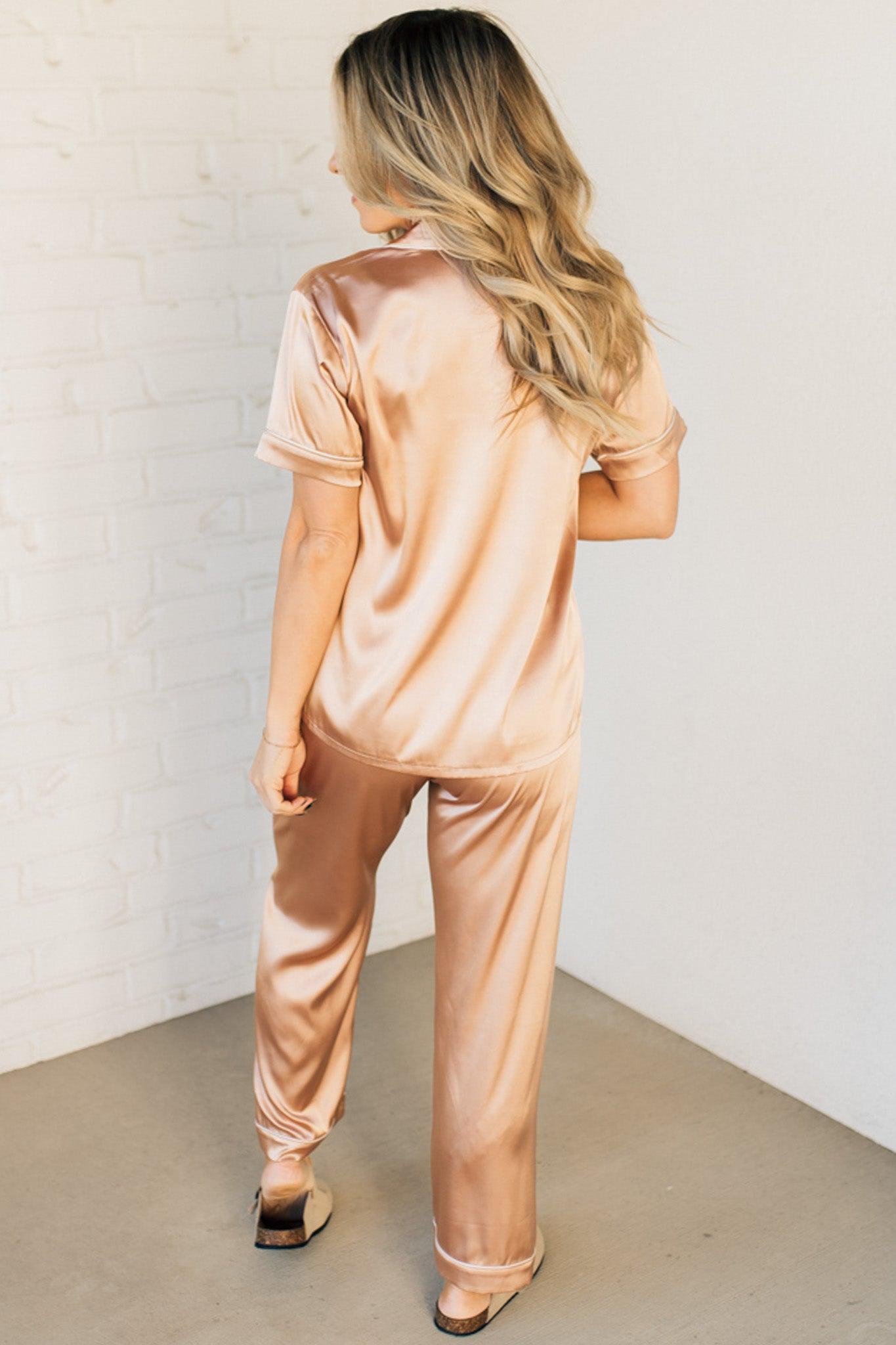 Blonde woman wearing a silk pajama set with white piping.