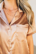 Blonde woman wearing a silk pajama set with white piping.