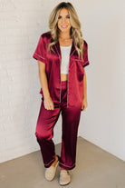 Blonde woman wearing a silk pajama set with white piping.