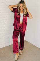 Blonde woman wearing a silk pajama set with white piping.