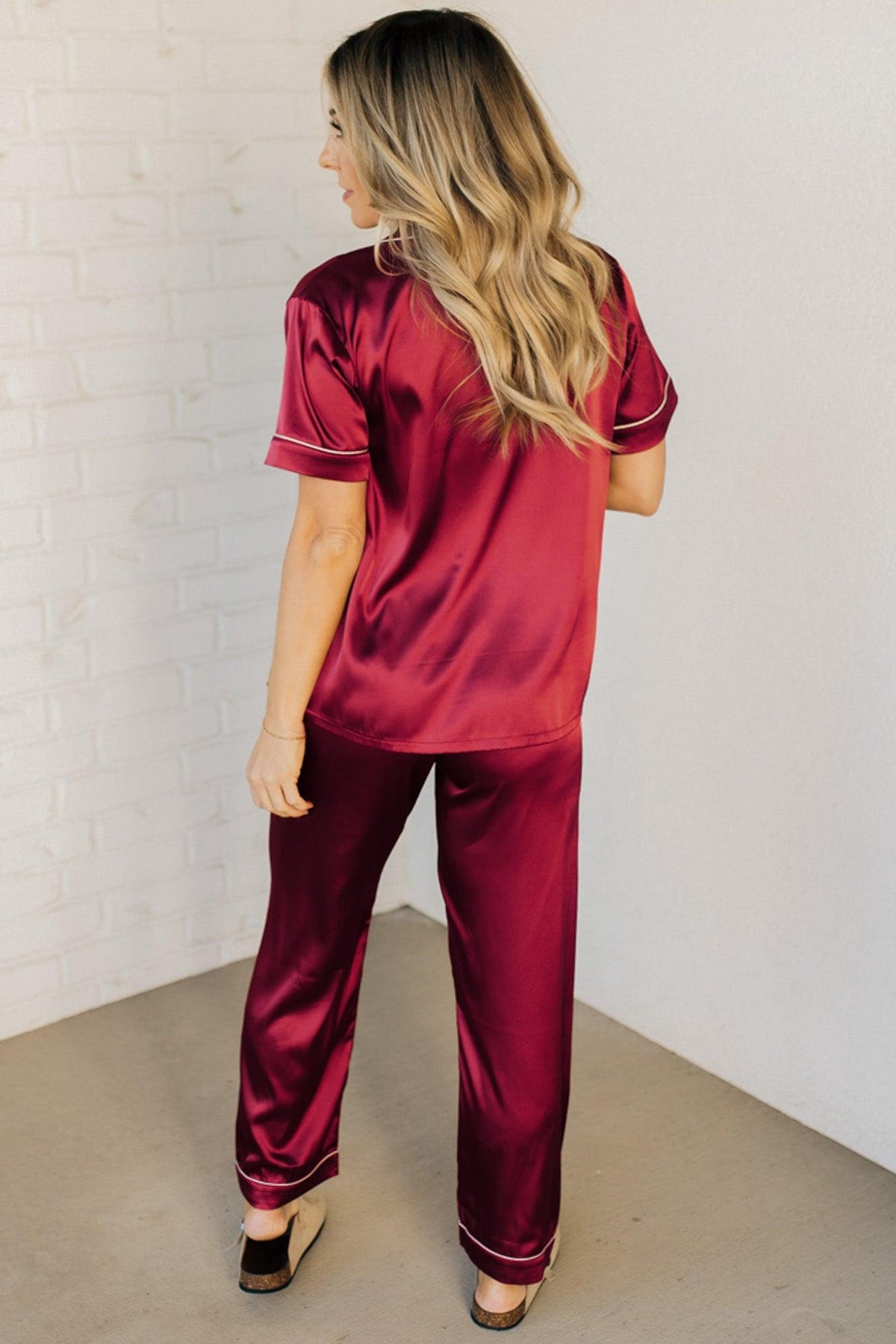 Blonde woman wearing a silk pajama set with white piping.