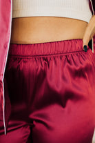 Blonde woman wearing a silk pajama set with white piping.