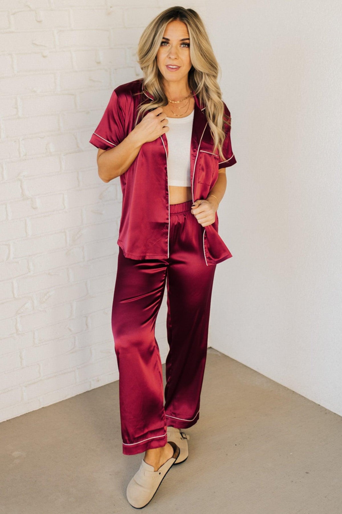 Blonde woman wearing a silk pajama set with white piping.