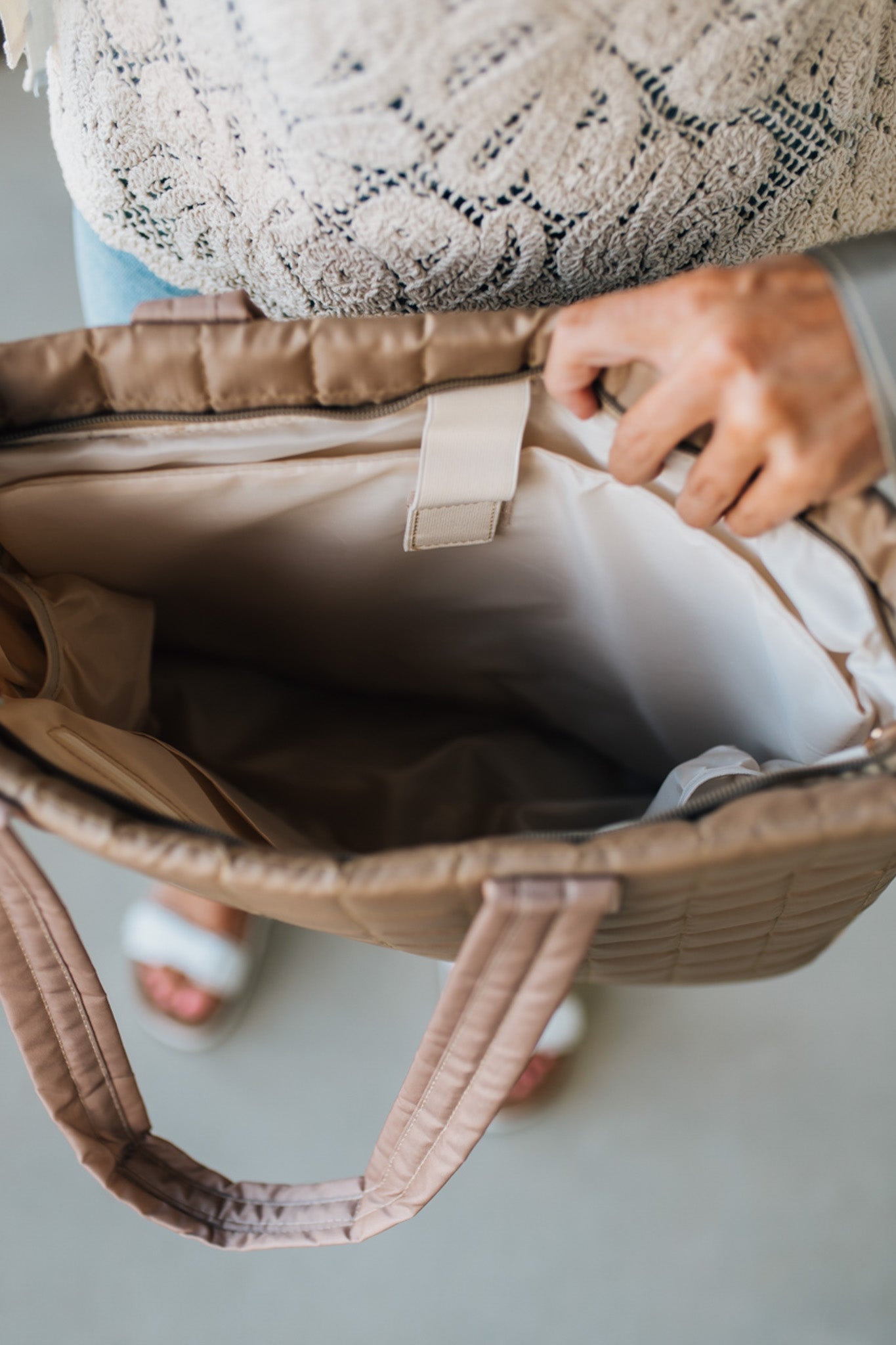 Woman holding a mocha nylon quilted traveler tote bag.