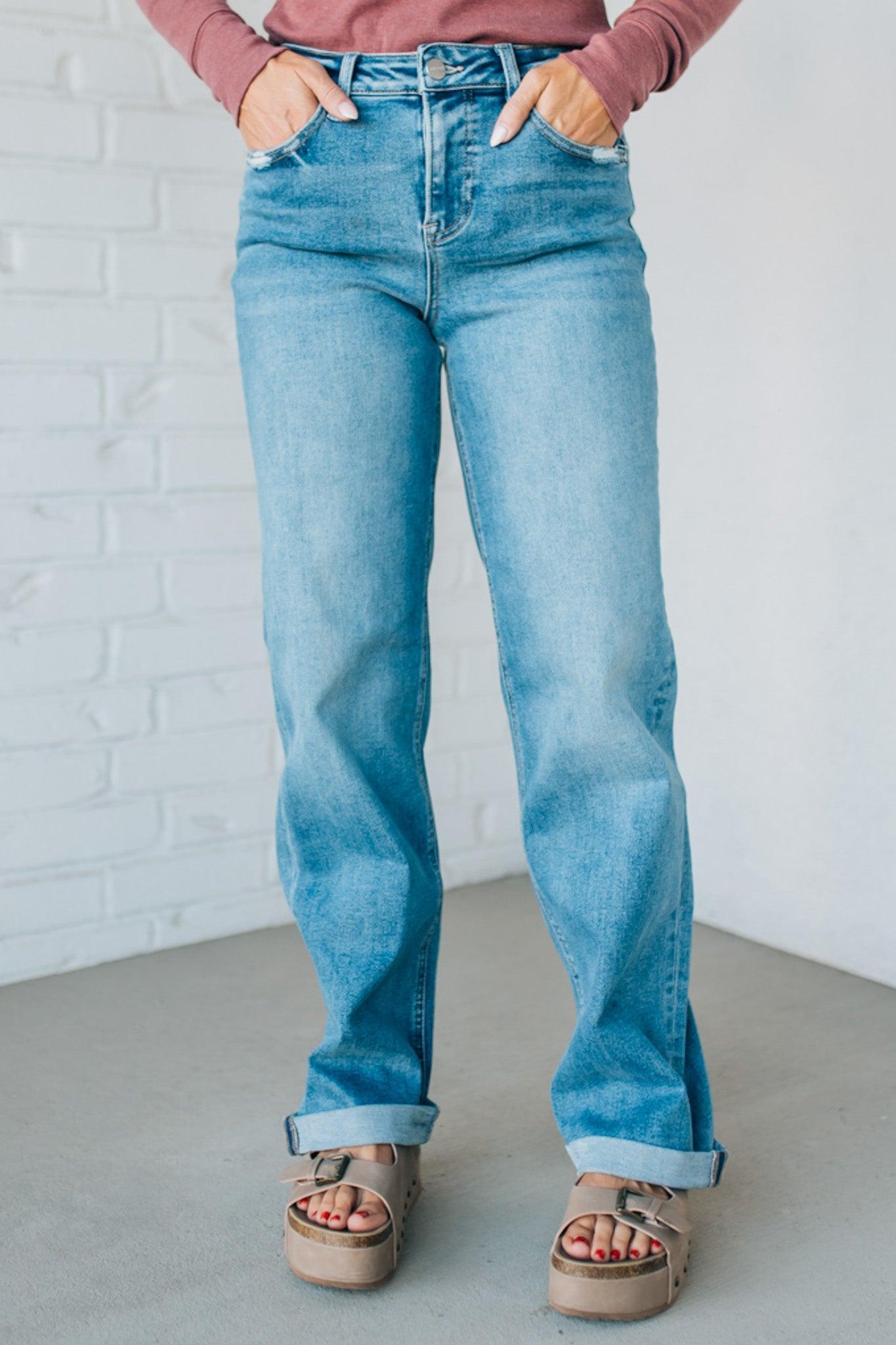 Person wearing blue jeans with a white brick wall background