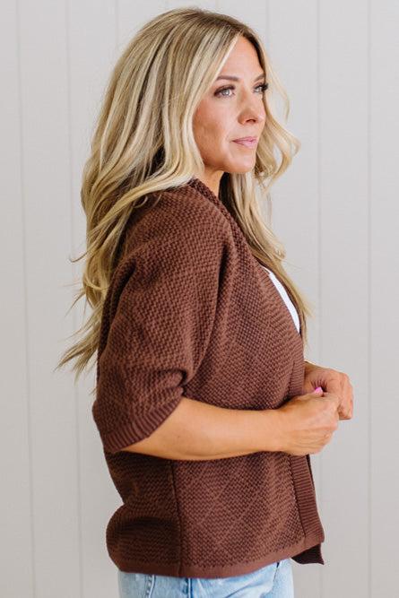 Woman wearing a brown knitted sweater against a plain background