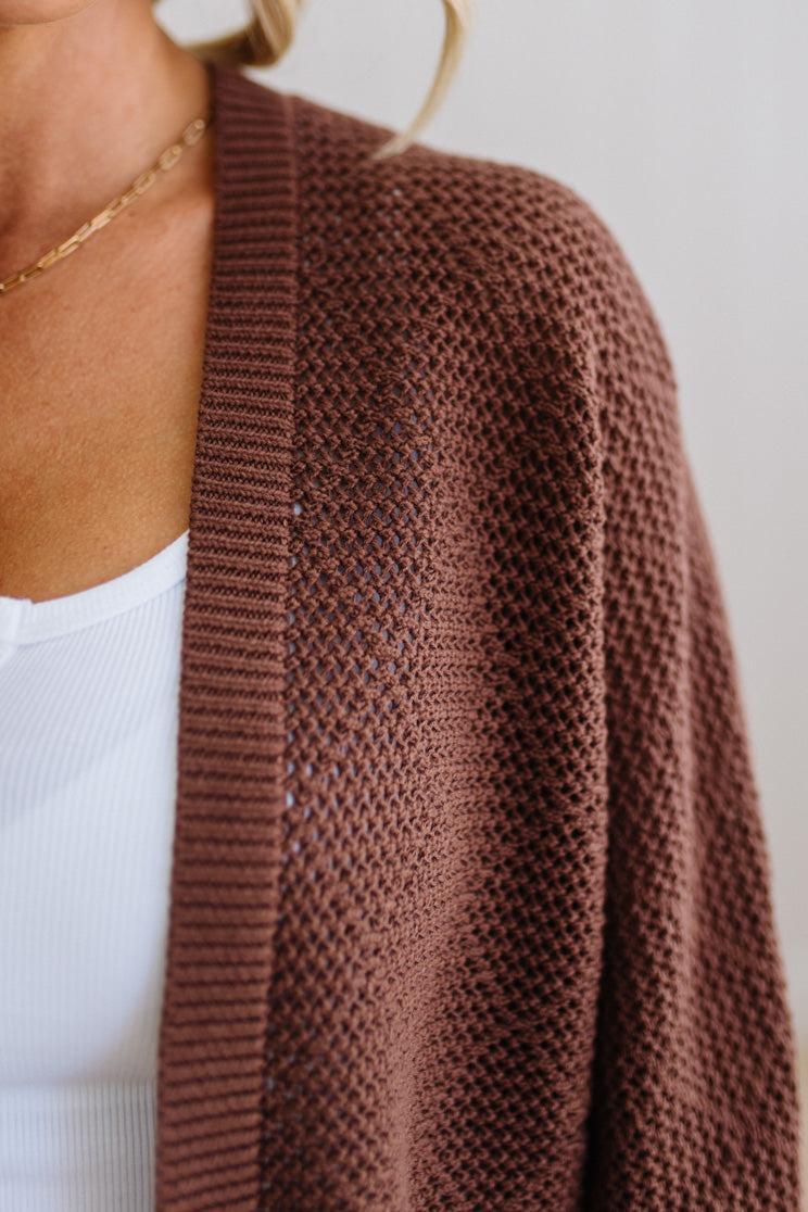 Brown knitted cardigan worn by a person on a plain background