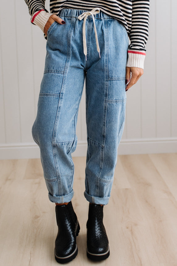 Person wearing light blue denim pants with a paneled wall background