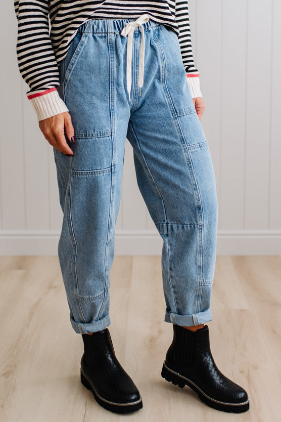 Person wearing light blue denim pants with a paneled wall background