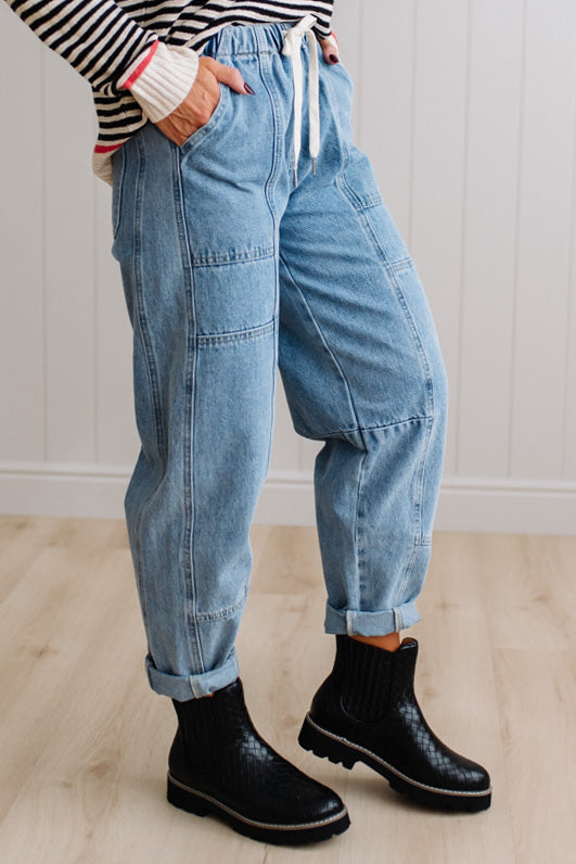 Person wearing light blue denim pants with a paneled wall background