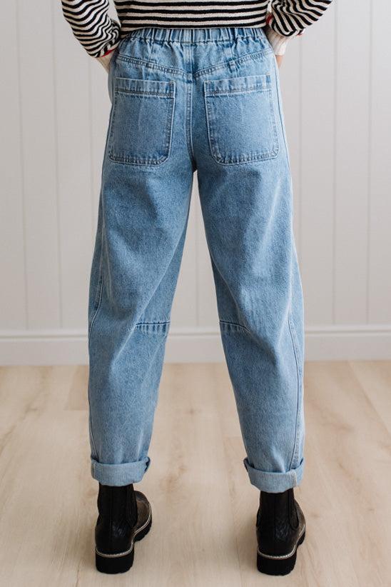 Person wearing light blue denim pants with a paneled wall background