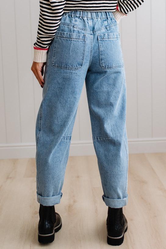 Person wearing light blue denim pants with a paneled wall background