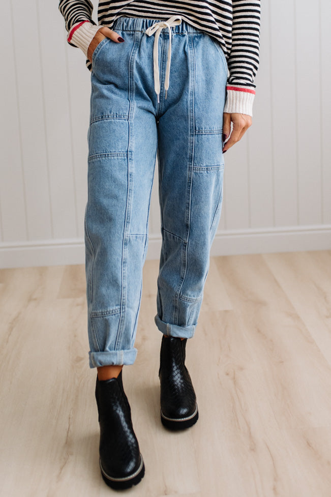 Person wearing light blue denim pants with a paneled wall background