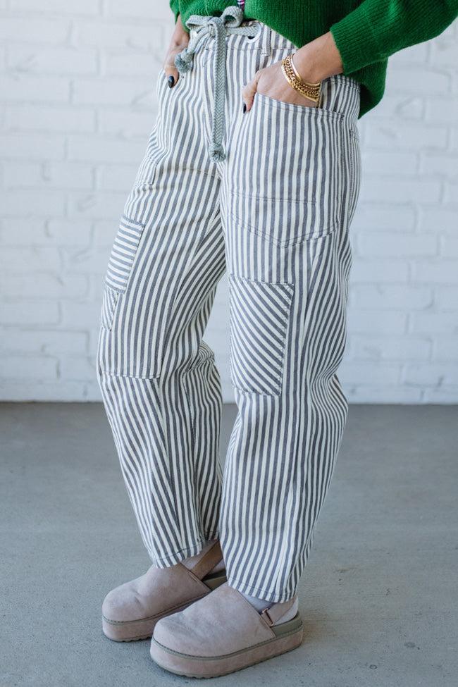 Woman wearing grey and cream vertical stiriped barrel cut jeans with a drawstring waist.