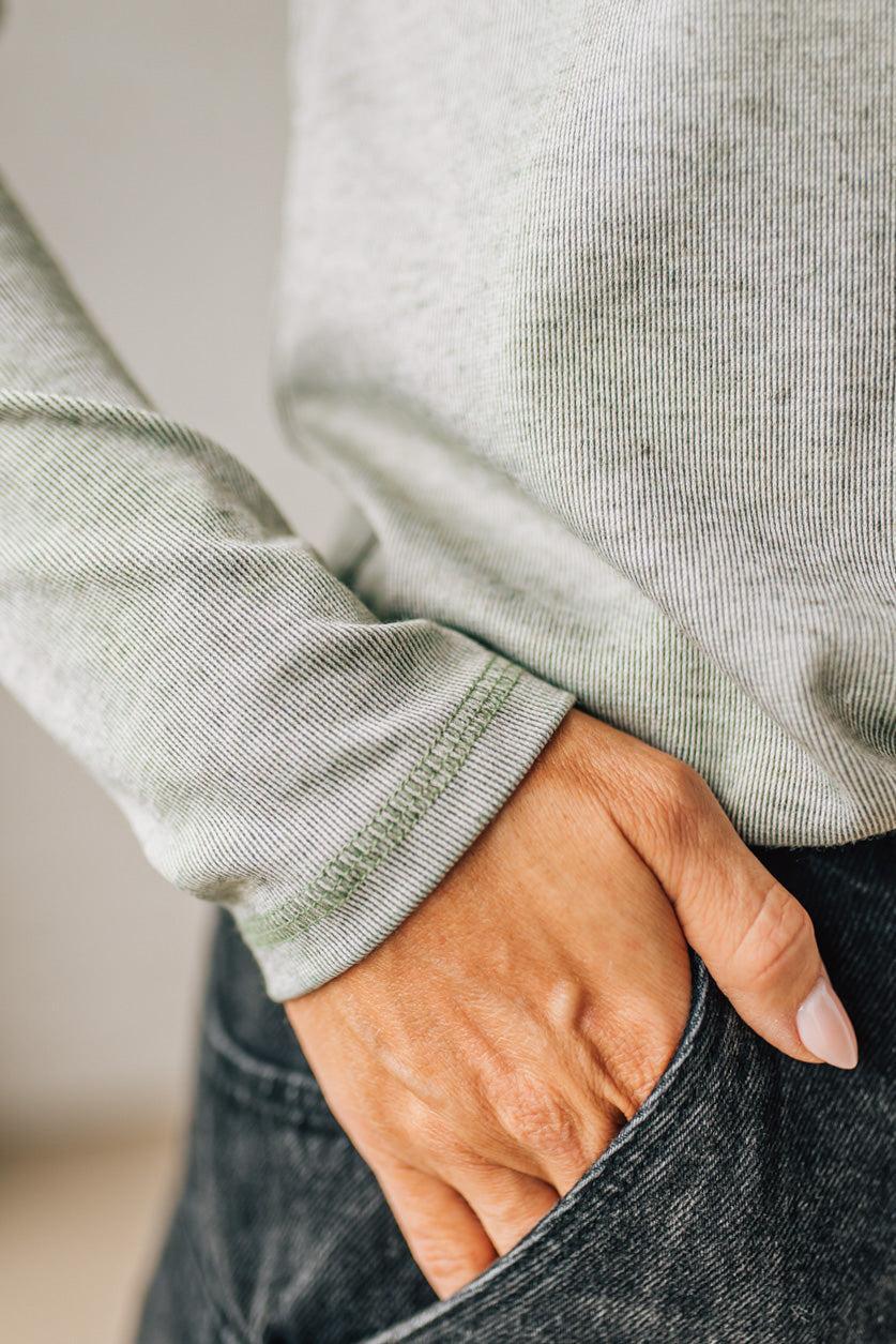 Person wearing a light green sweater with a blurred background