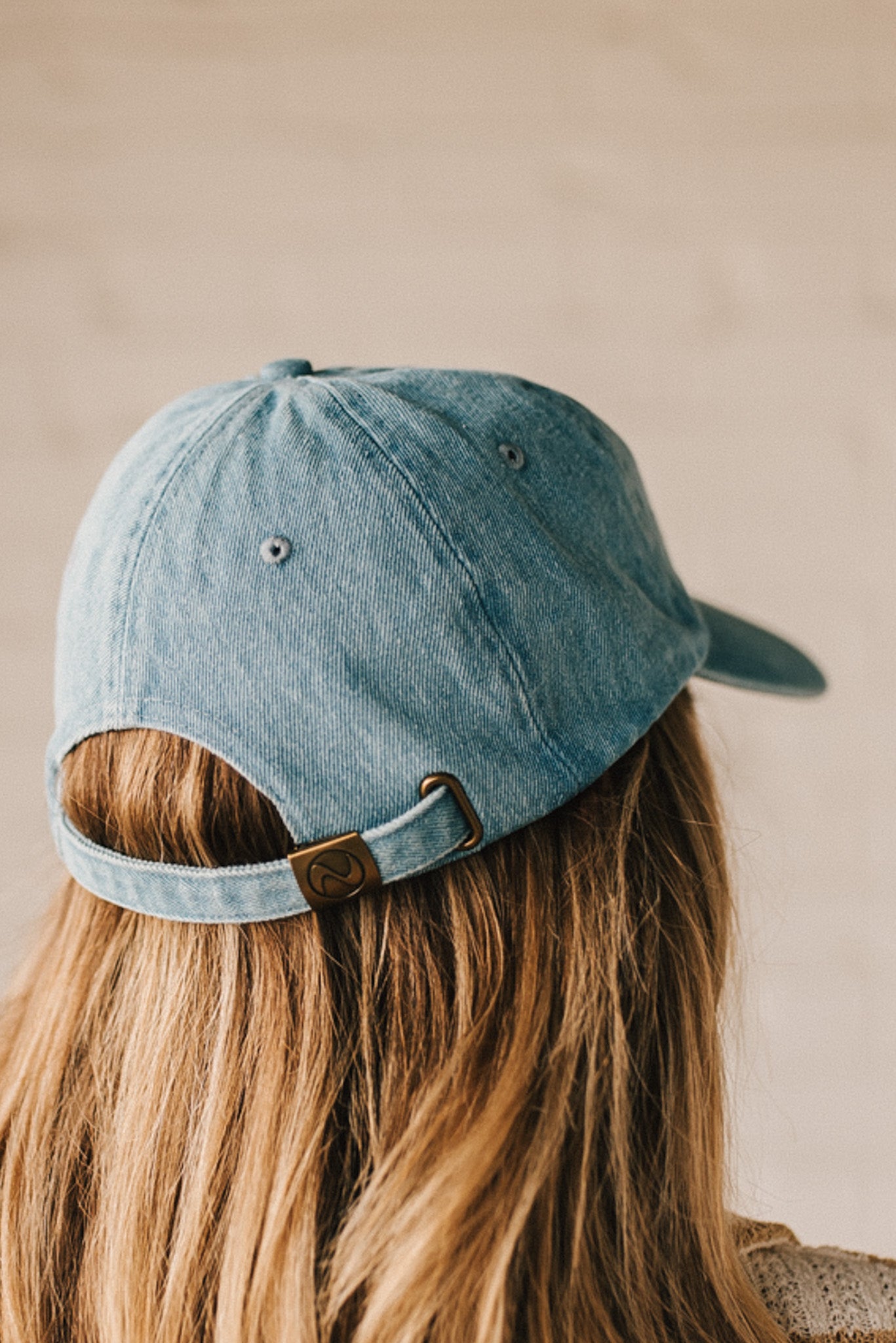 Blonde woman wearing a denim Hat with embroidered King Cavalier dog at front center.
