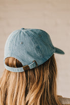 Blonde woman wearing a denim Hat with embroidered King Cavalier dog at front center.