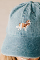 Blonde woman wearing a denim Hat with embroidered King Cavalier dog at front center.