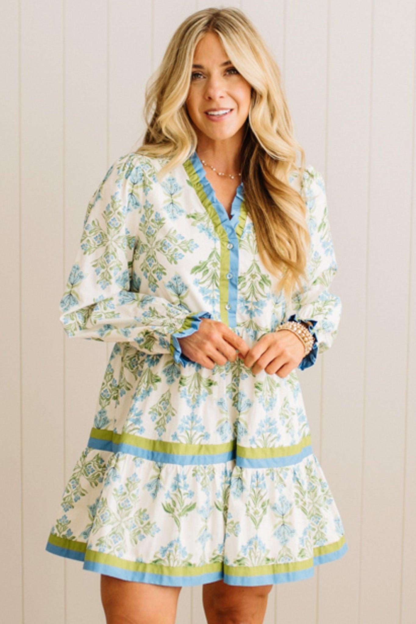 Woman wearing a floral dress with long sleeves against a wooden panel background