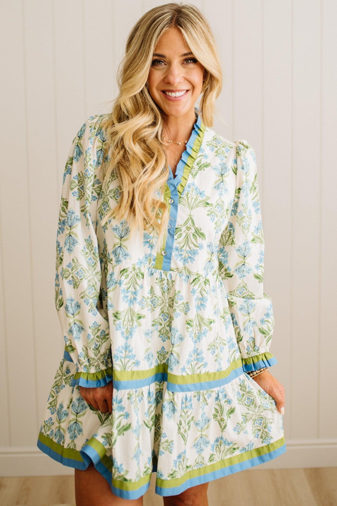 Woman wearing a floral dress with long sleeves against a neutral background