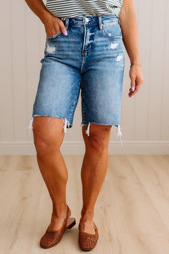 Person wearing blue denim shorts with a neutral background