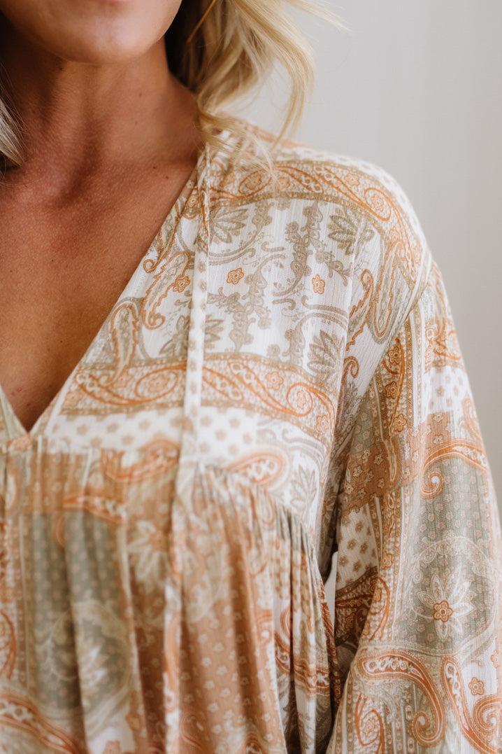 Close-up of a person wearing a patterned blouse with neutral tones.