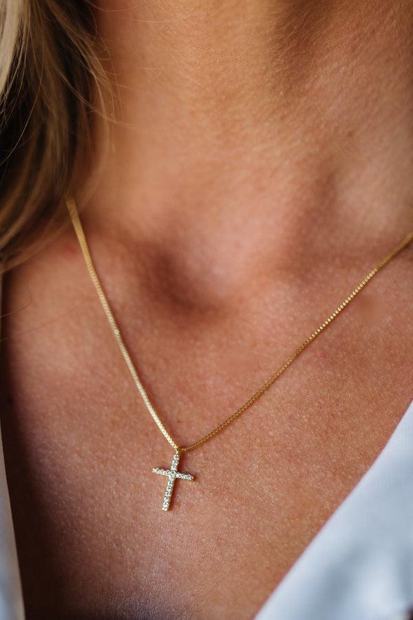 Gold necklace with a cross pendant on a person's neck