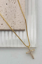 Gold necklace with a cross pendant on a light background