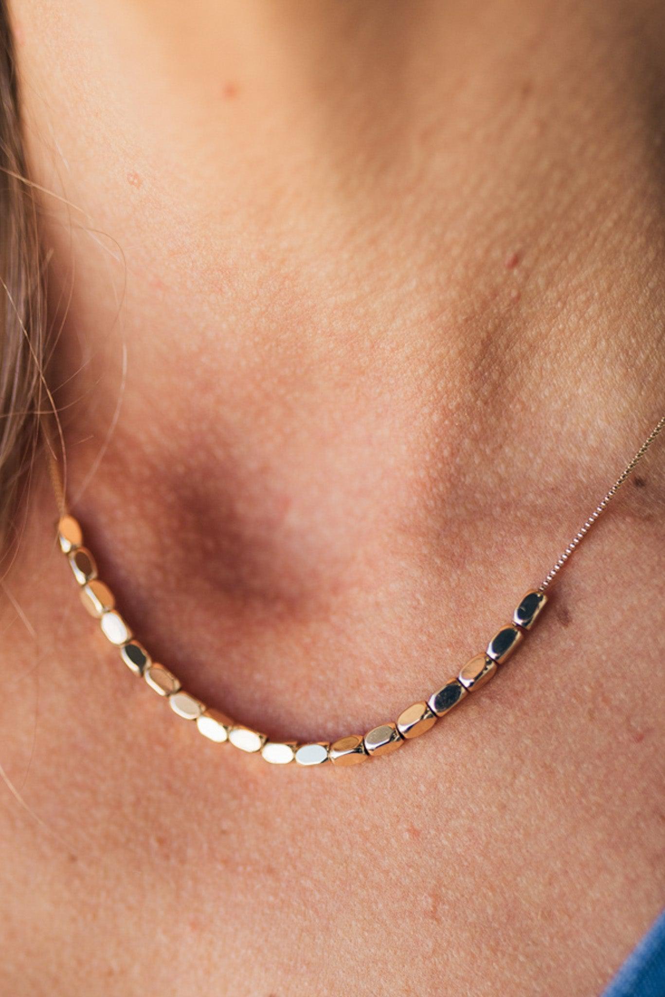A minimalist beaded necklace with gold plating and small gold beads