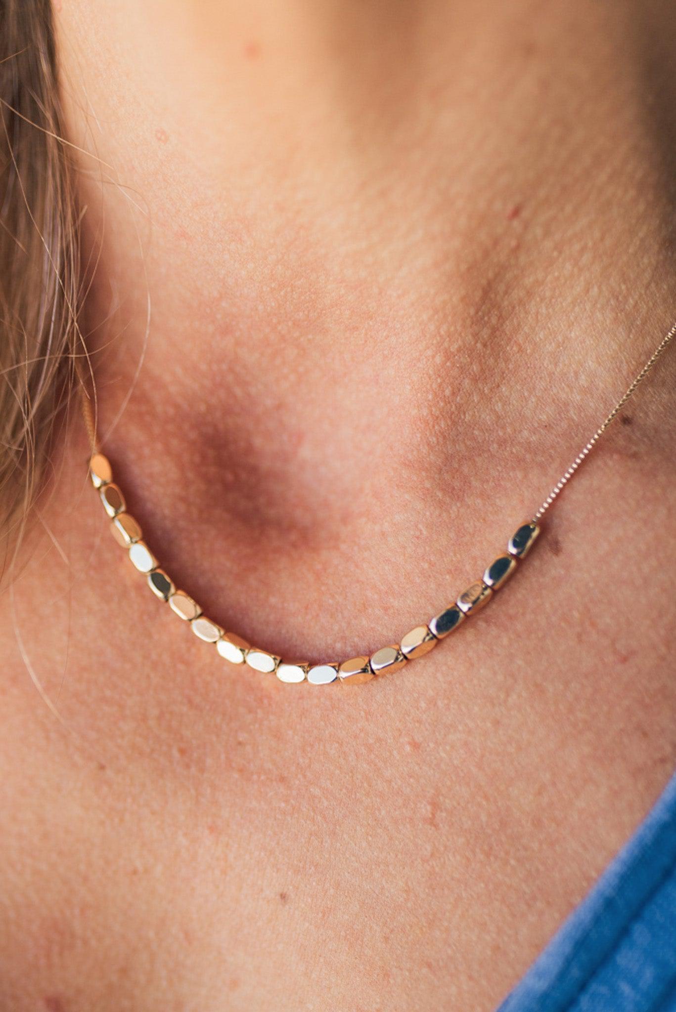 A minimalist beaded necklace with gold plating and small gold beads.