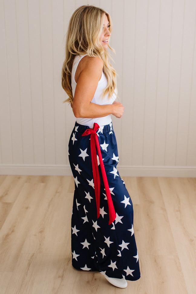 Person wearing a pair of wide-leg pants with star pattern and a red sash.