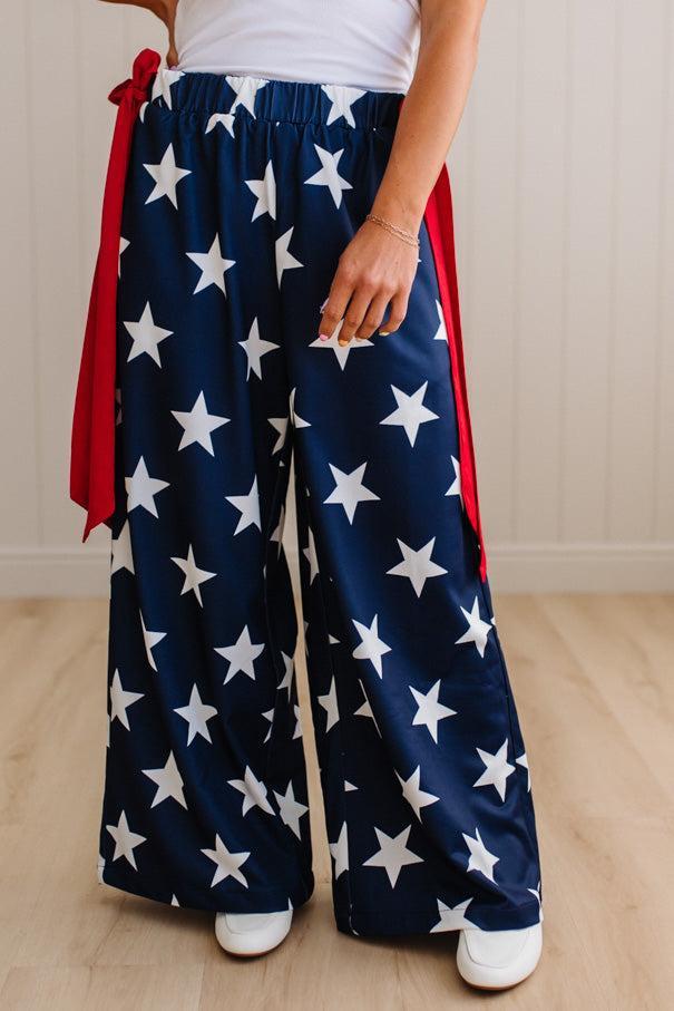 Person wearing blue pants with white star pattern and red accents on a light wooden floor.