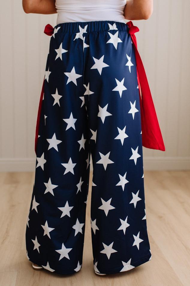 Person wearing a pair of wide-leg pants with star pattern and a red sash.