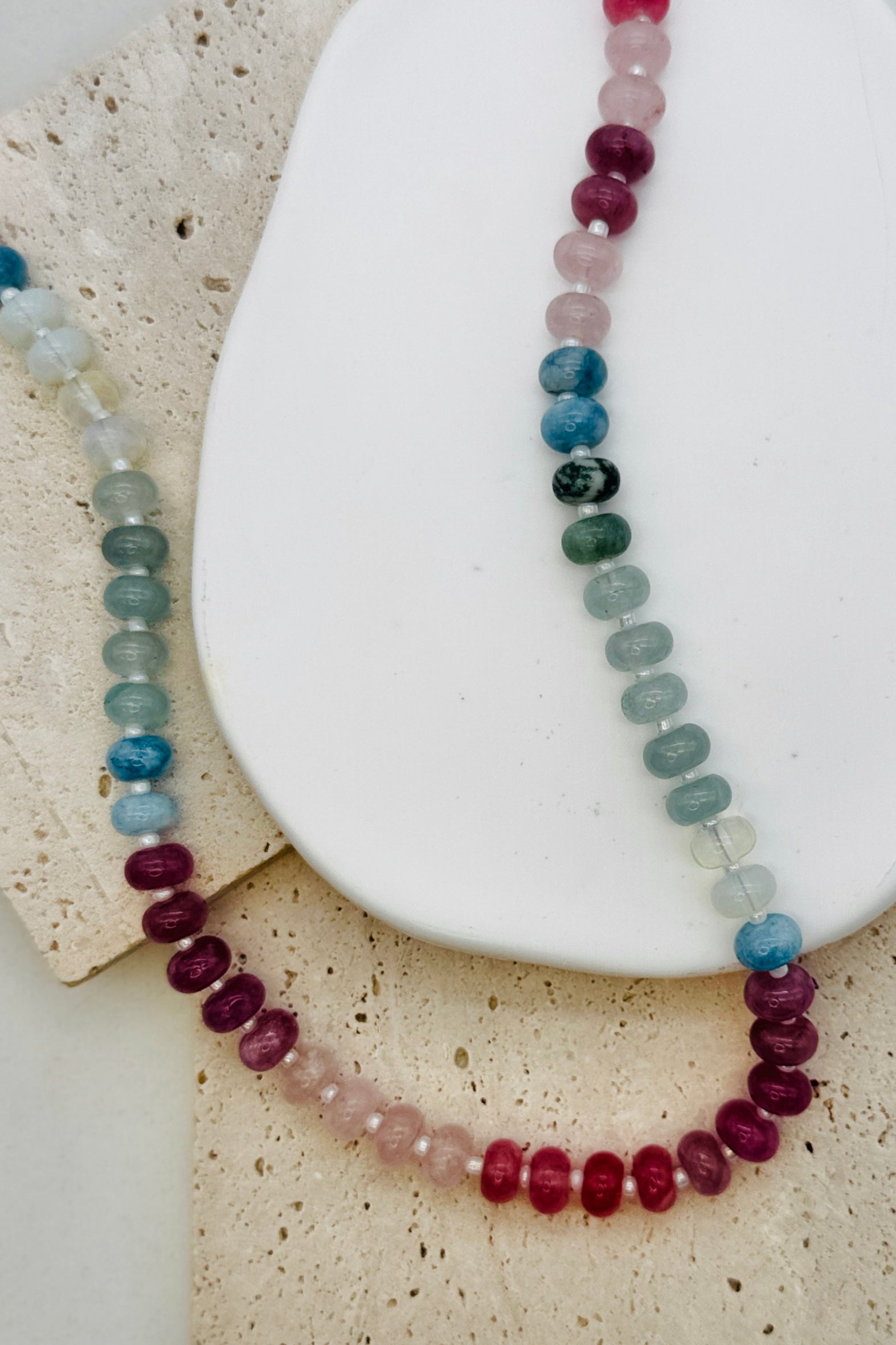 Necklace with multicolored beads on a white stone surface