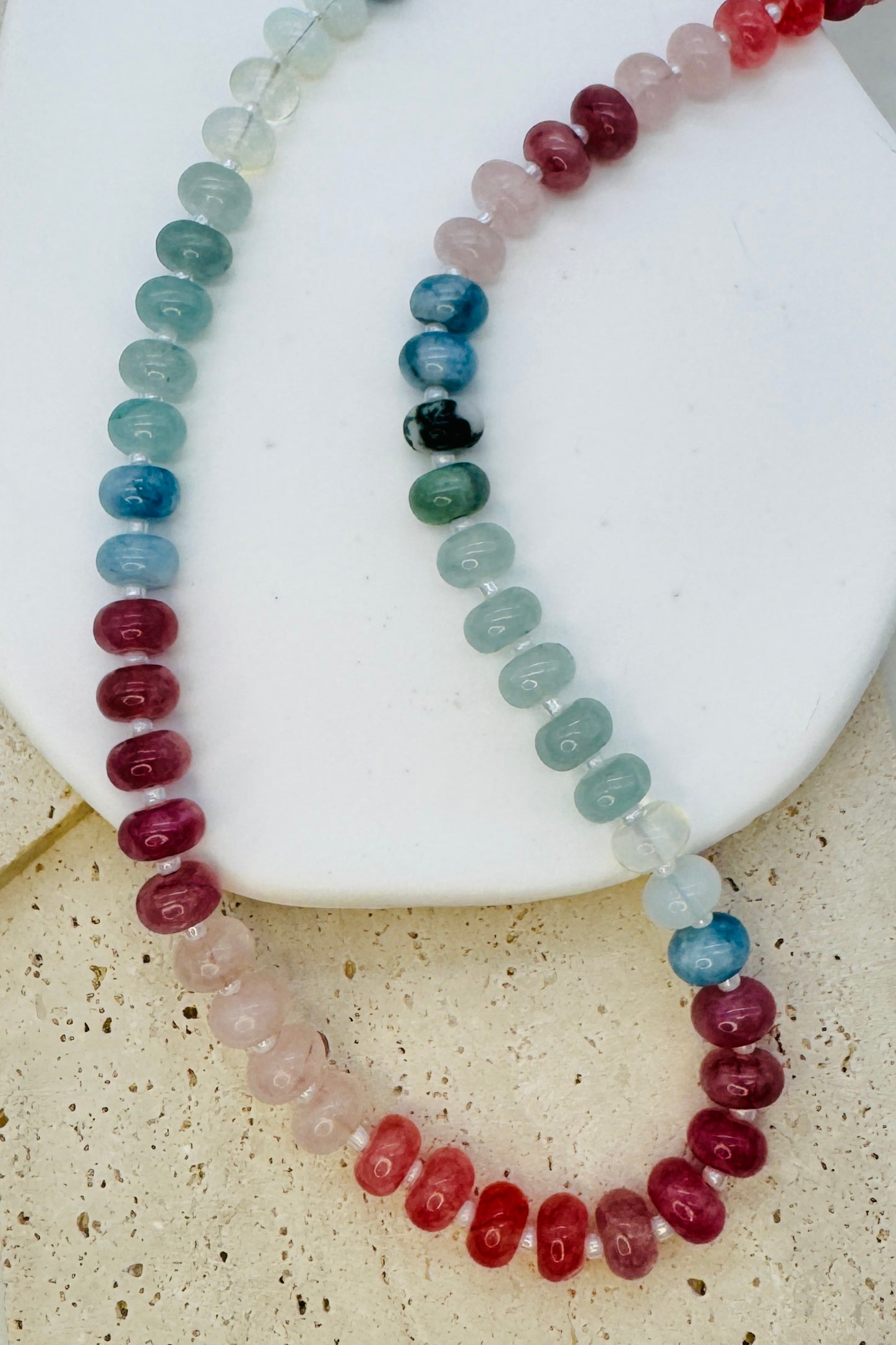 Two beaded necklaces on a white stone surface