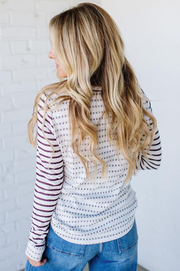 Woman wearing a striped long-sleeve top and jeans against a white background