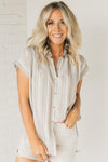 Woman wearing a short sleeve button down top with slim stripes in muted fall toned colors.