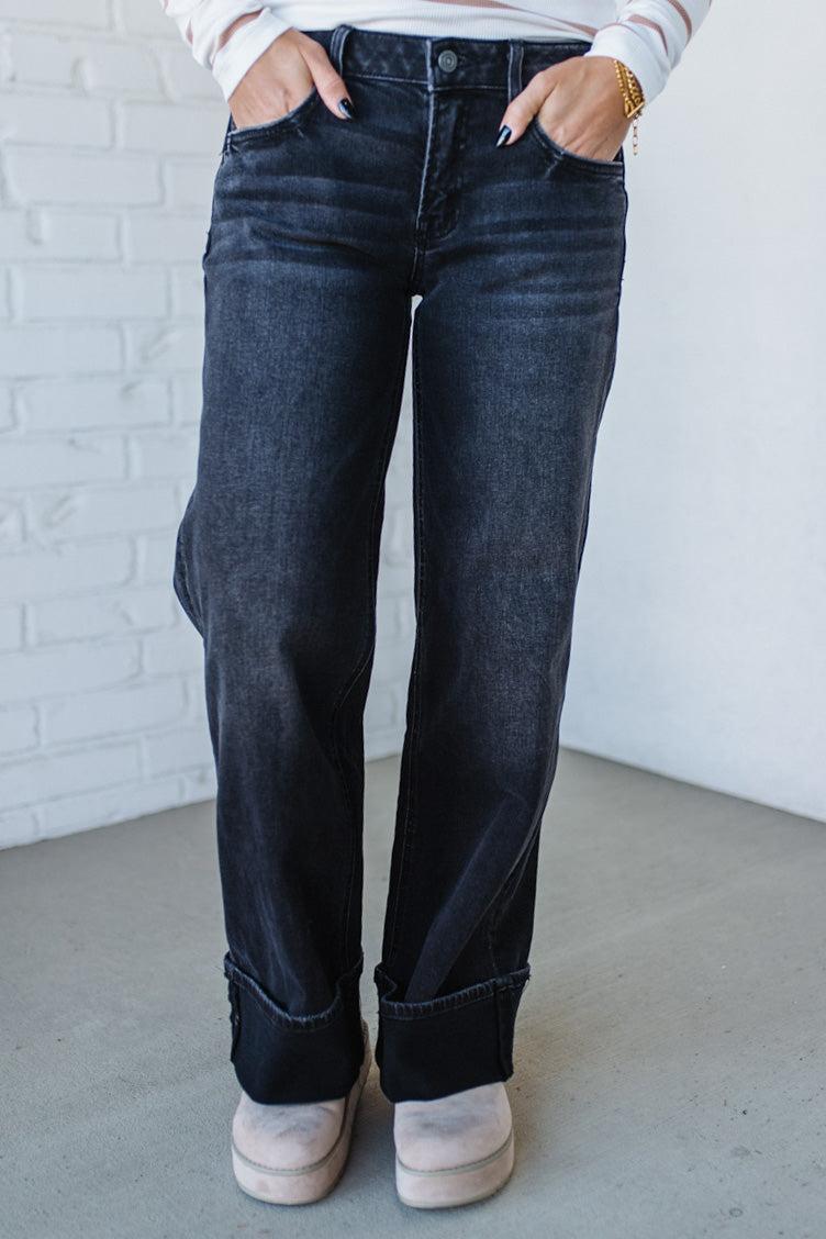 Person wearing dark blue jeans with a white brick wall background