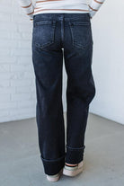 Person wearing dark blue jeans with a white brick wall background
