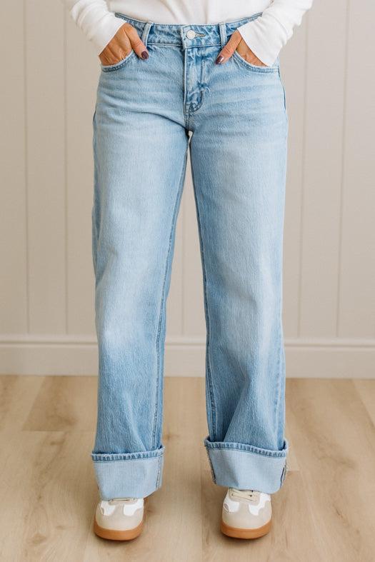 Light blue jeans worn by a person on a wooden floor with a neutral wall background