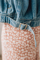 Blonde woman wearing a medium wash zip front denim moto jacket.