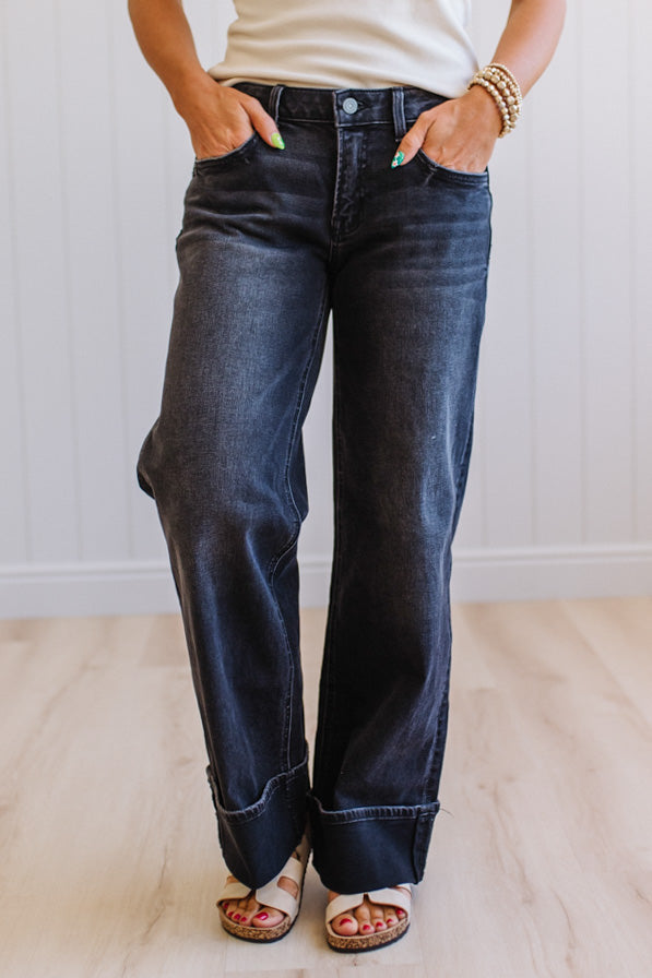 Person wearing dark blue jeans with a plain background
