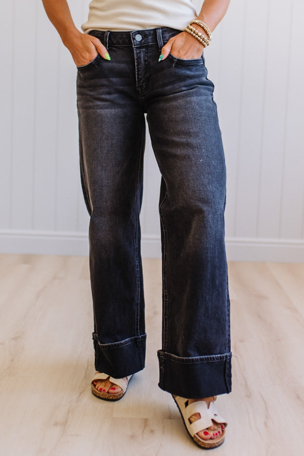 Person wearing dark blue jeans with a plain background