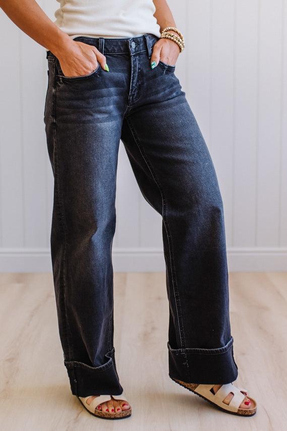 Person wearing dark blue jeans with a plain background