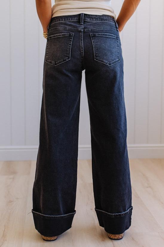 Person wearing dark blue wide-leg jeans with a white background